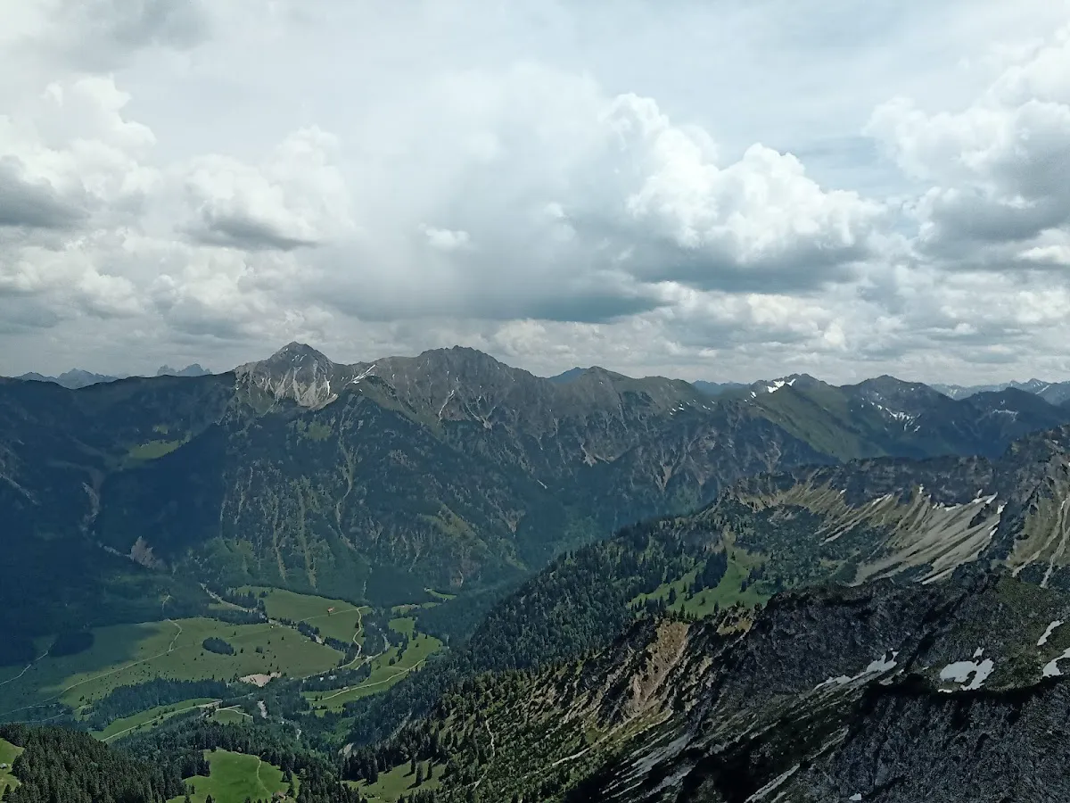 Silhouette of hiker on exposed ridge with Forggensee and Neuschwanstein in distant valley