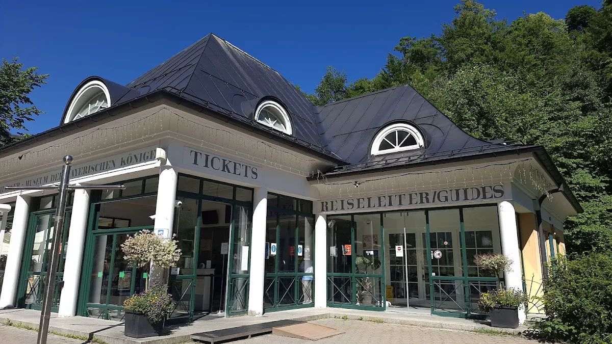 Tegelberg Via Ferrata climber on exposed rock face with castle in distance below