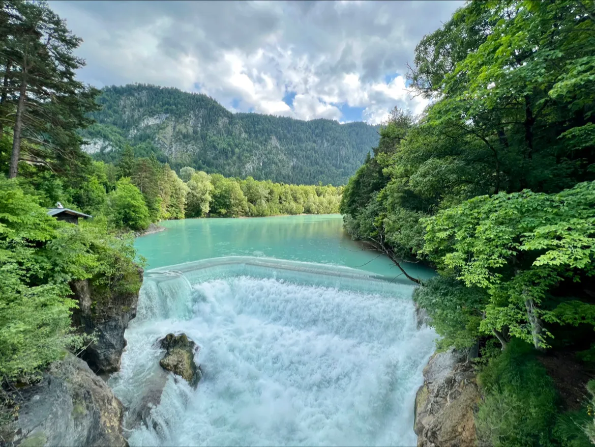 Alatsee lake with mirror-calm turquoise water surrounded by dramatic mountain amphitheater