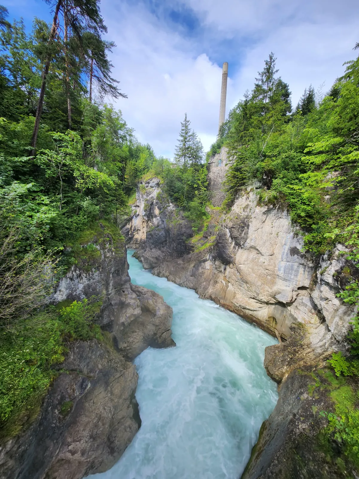 Turquoise waters of Lechfall cascading over historic weir with Alps backdrop