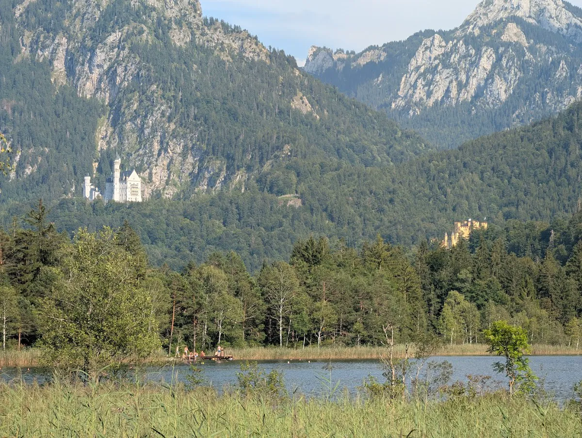 Schwansee Kiosk on the shore with peaceful lake and forest backdrop