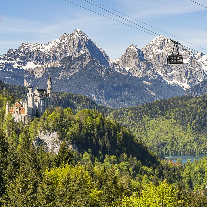 Paraglider launching from the Tegelberg summit with Neuschwanstein Castle far below