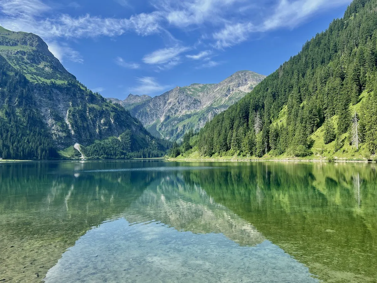 Morning mist rising from crystal clear Vilsalpsee with mountain reflections